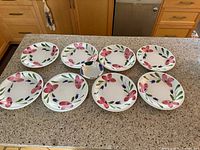 All eight plates and bowl laid out on countertop showing design and quantity