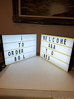 Two illuminated message boards side by side displaying letters