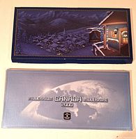 Two closed coin set folders, one blue snowy village, one silver earth design