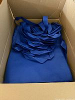 Open box showing stack of royal blue tote bags