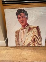 Head and torso portion of Elvis Presley image in gold suit inside packaging