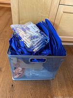 Mesh metal bin filled with blue items (bags, lanyards) and pens