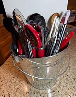 bucket filled with assorted serving utensils