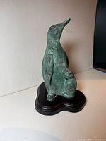 Front-left view of patina bronze-look penguin on dark wood base