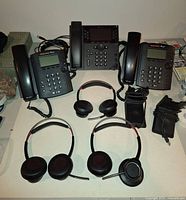 Group view of three Polycom phones, three headsets, two stands, cables