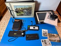 Group shot of four cameras, digital photo frame, album, postcard prints