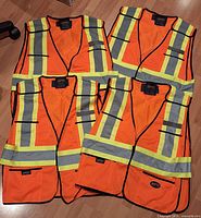 Four Pioneer orange reflective vests laid out