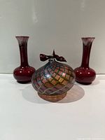 Front view showing glass ornament centered between two red pottery vases