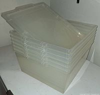 Stack of seven clear plastic storage containers with lids attached