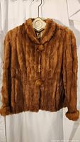 Front view of closed light brown mink jacket on hanger