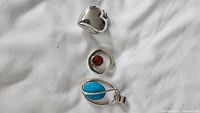 All three sterling pendants laid out: heart, amber, turquoise