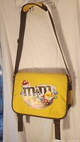 Front view of yellow M&M's messenger bag with logo