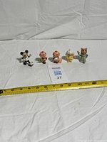 All five PVC figures lined up on white background with tape measure for scale