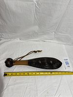 Full view of carved mere with wrist cord beside ruler showing length