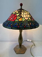 Full view of lamp lit, showing stained glass shade and metal base