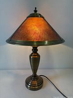 Front view of Mission style table lamp lit, showing amber mica shade and metal base