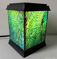 Lamp illuminated showing rippled stained glass panels and metal frame