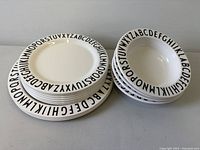 Stack of plates and bowls showing alphabet rim design