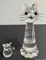 Front view of both crystal cat figurines on black surface