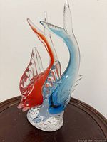 Front view of red and blue Murano glass twin fish sculpture on base