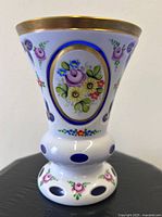 Front view of white overlay cobalt vase showing floral panel and cut oval windows
