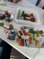 Group of assorted die-cast vehicles on table and in bin