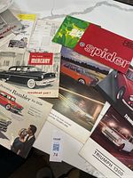 Spread of assorted brochures showing Mercury, Rambler, Triumph 1300, Spider, colour photo sheets and green price list