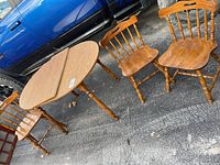 Table with leaf extended beside three wooden chairs