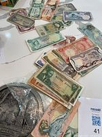 Overview of assorted banknotes spread on table with pewter plaque partially visible