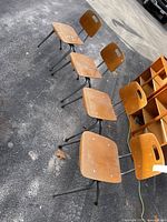 Five matching metal-frame wood school chairs on driveway