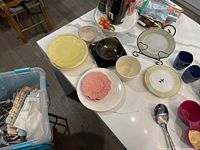 countertop with plates, bowls, mugs, serving spoon