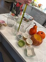 Group view of vases, pumpkins, bowls and pails on countertop
