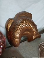 Copper-tone fish mold close-up showing patina