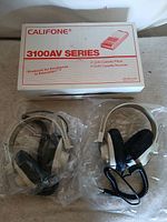 Both headphones in plastic sleeves beside original box