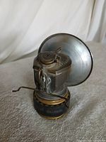 Front view of carbide lamp showing water chamber, reflector, and filler cap