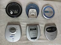Six portable CD players laid out on towel