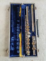 Flute disassembled into headjoint, body, footjoint inside blue velvet lined hard case with yellow cloth visible