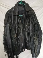Front view of black leather jacket showing fringe and zippered front