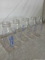 Five Evenflo Nursematic glass baby bottles standing in row