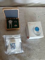 Overview showing Brookstone Bob clock box, wooden case with divot tool and cufflinks, sealed night light clip