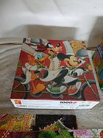 Disney 1000-piece puzzle box showing Mickey, Donald, Goofy on bicycle