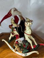 Santa on cream rocking horse with elves and gifts