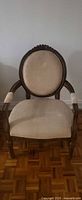 Front view of chair showing carved wood frame, upholstered oval backrest and seat