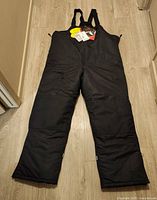 Full view of black EDCO snow pants laid flat