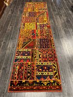 Full view of entire Persian patchwork runner rug on dark floor