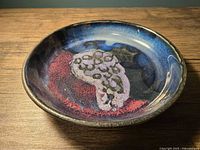 Top view of glazed pottery plate showing grape motif