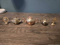 Front view of five miniature copper and brass items aligned on surface