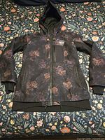 Full view of jacket front showing floral pattern, hood, pockets