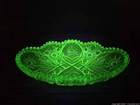 Dish glowing bright green under UV, showing fluorescence and pattern