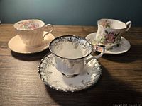 Three branded bone china teacups with saucers displayed